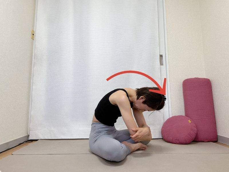 あぐらで座り、体の前で肘を抱え背骨を丸めて上体を前に傾けた体勢