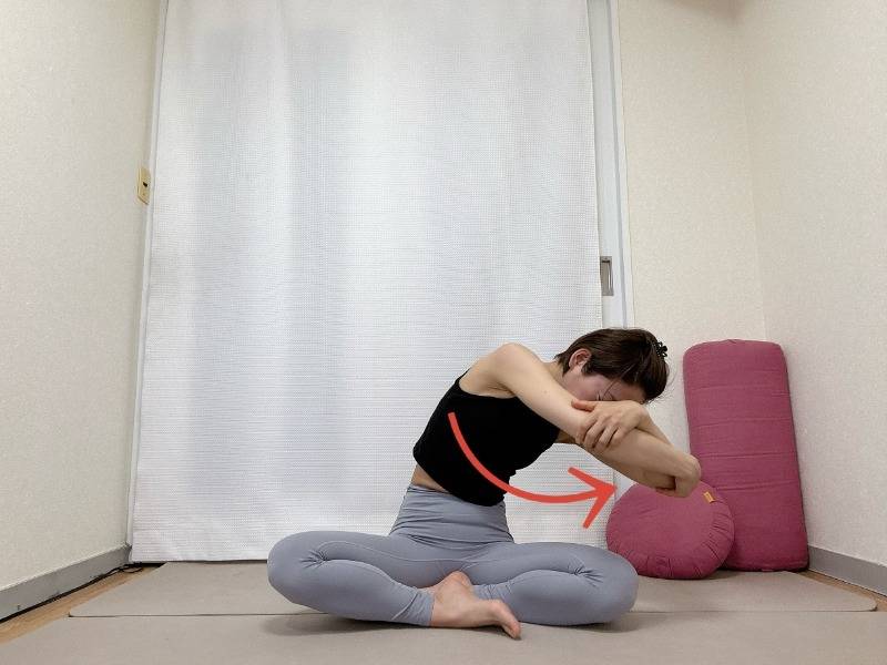 あぐらで座り体の前で両肘を抱え、背骨を丸めながら肘を右に引いた体勢