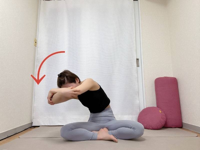 あぐらで座り体の前で両肘を抱え、背骨を丸めながら肘を左に引いた体勢