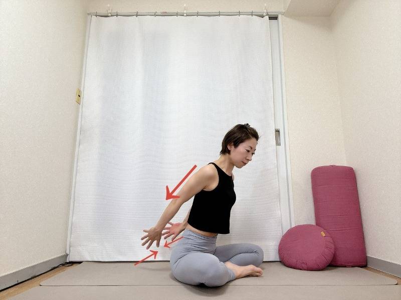 あぐらで座り、上体を目に傾け腕を後ろに伸ばして内側に寄せる上腕三頭筋のエクササイズ