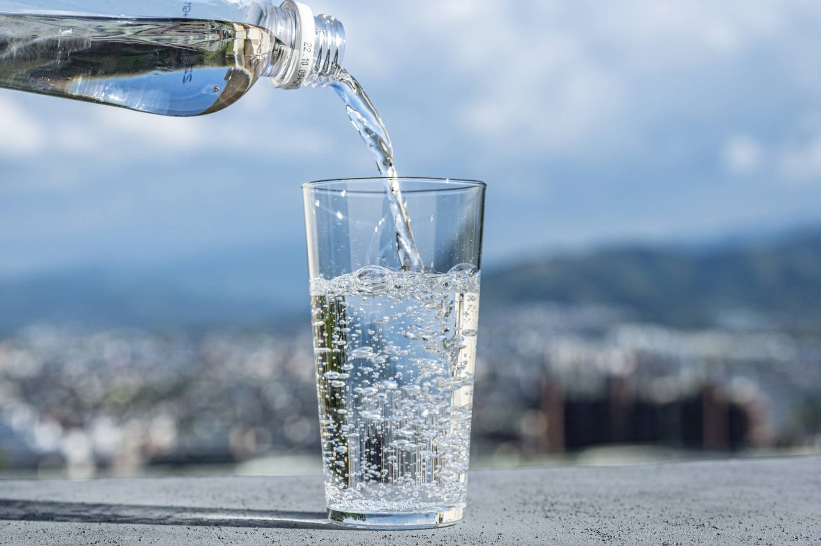 屋外でペットボトルからグラスに注がれる炭酸水