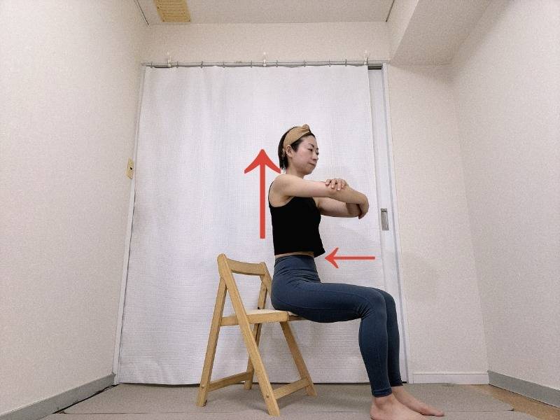 肘を胸の前で抱えて椅子に浅めに座った体勢