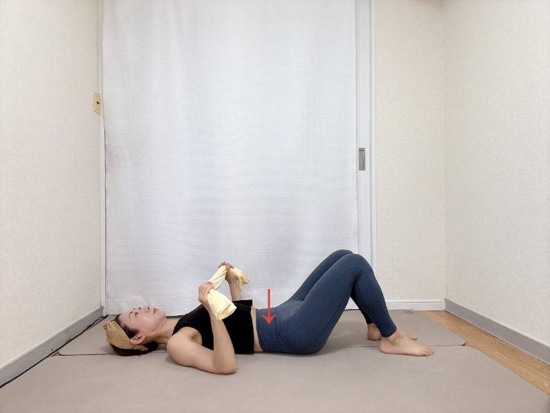 両手でタオルの端を持ち、膝を立てた仰向けで寝た体勢
