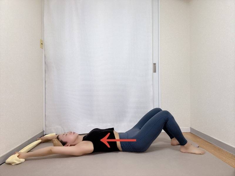 膝を立てた仰向けでタオルを持ち、タオルを引っ張りながらバンザイしてお腹を伸ばすストレッチ