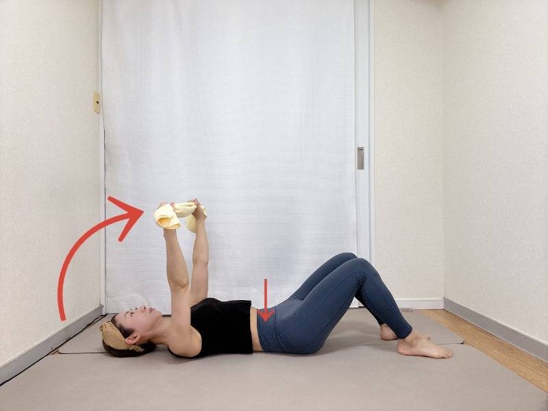 膝を立てた仰向けでタオルを持ち、引っ張りながら天井方向に腕を伸ばした体勢