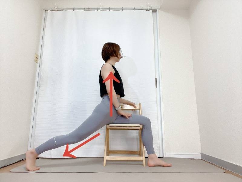 椅子の背もたれが体の右側にして横向きで座り、膝を伸ばして左脚を後ろに引いた体勢