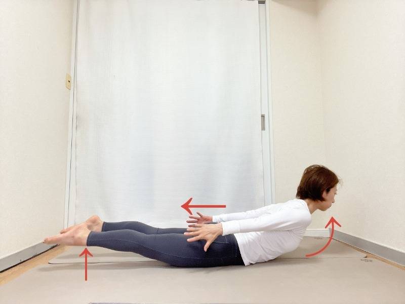 うつ伏せから、両手を後ろへ伸ばし、上体と脚を床から浮かせたバッタのポーズ