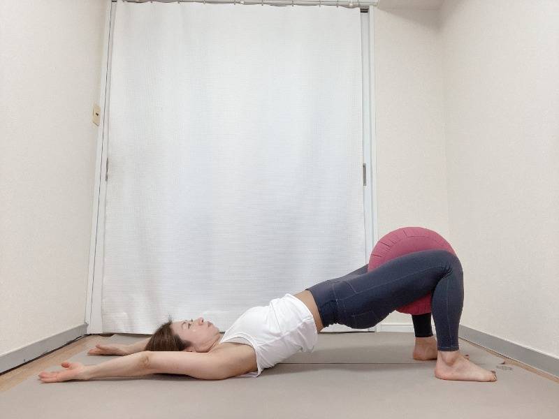 太腿の間にクッションを挟み、内転筋を刺激しながら行う橋のポーズ