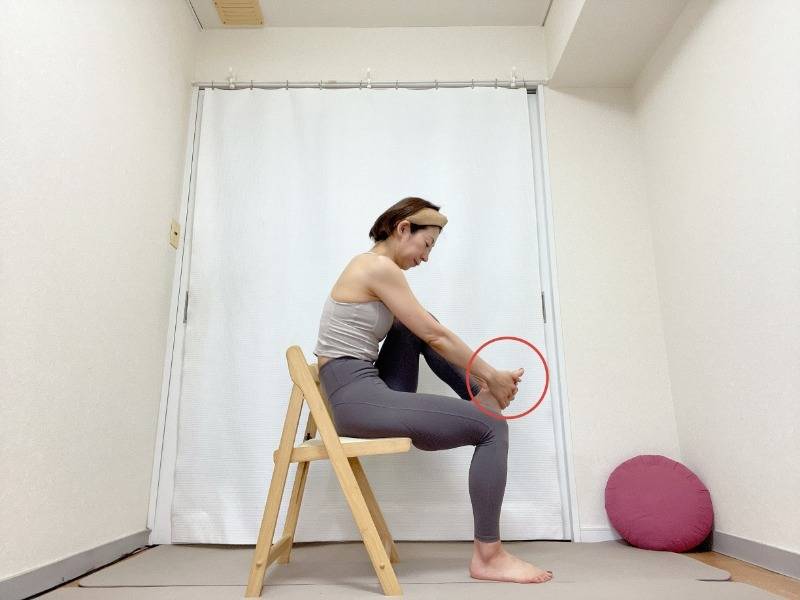 椅子に座り、右足の裏を両手でつかんだ体勢
