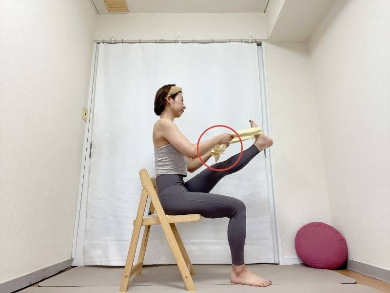 タオルを足の裏にかけて、椅子に座ってふくらはぎや太腿の裏を伸ばす行うサギのポーズストレッチ
