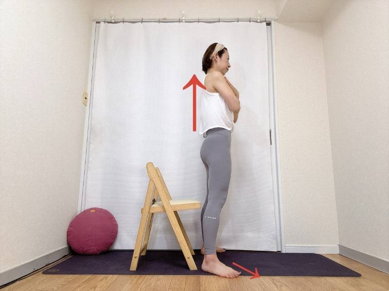 両手を胸の前でクロスし、椅子の前に立った体勢