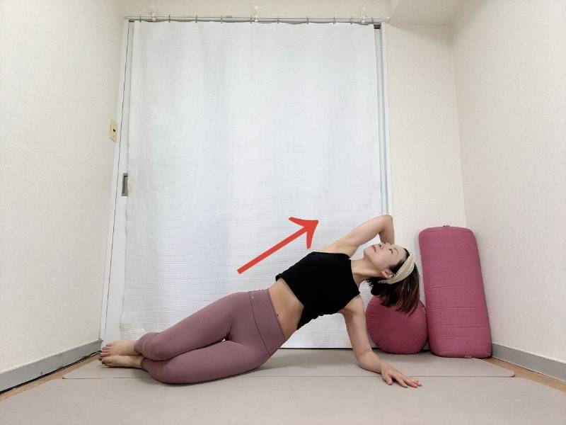 右肘を床につき、両膝を曲げて上体を右に倒した横向き寝の姿勢から右肘で床を押し、左体側を伸ばして胸を開いた体勢