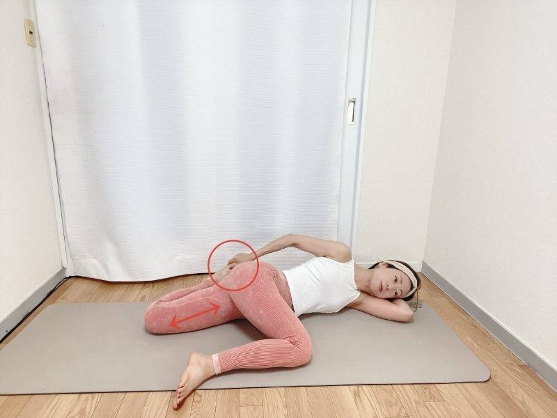 左脚を体の前で曲げた左向きの横向きから左手で右足首を掴んで右腿の前～外側を伸ばすストレッチ