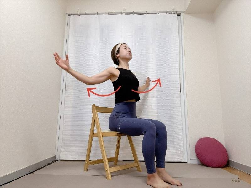 椅子に座り、軽く肘を曲げて腕を横に開くストレッチ