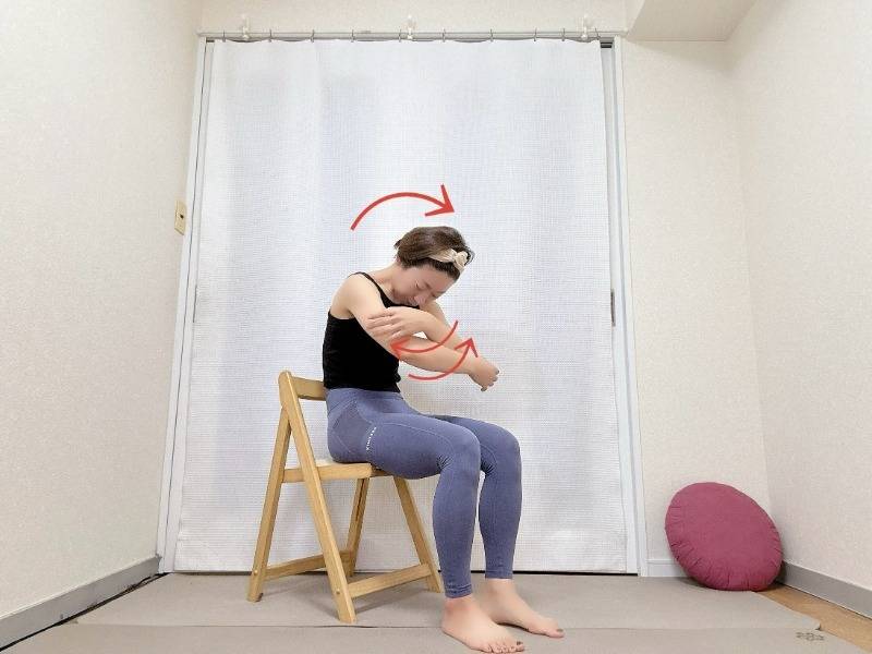 椅子に座り、背中を丸めて胸の前で両手をクロスした体勢