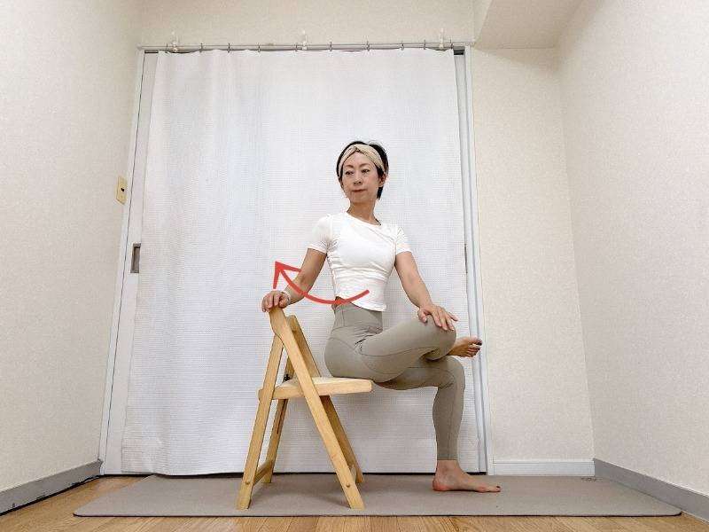椅子に座り、左脚を右腿に乗せて4の字を作り、上体を左に捻るストレッチ