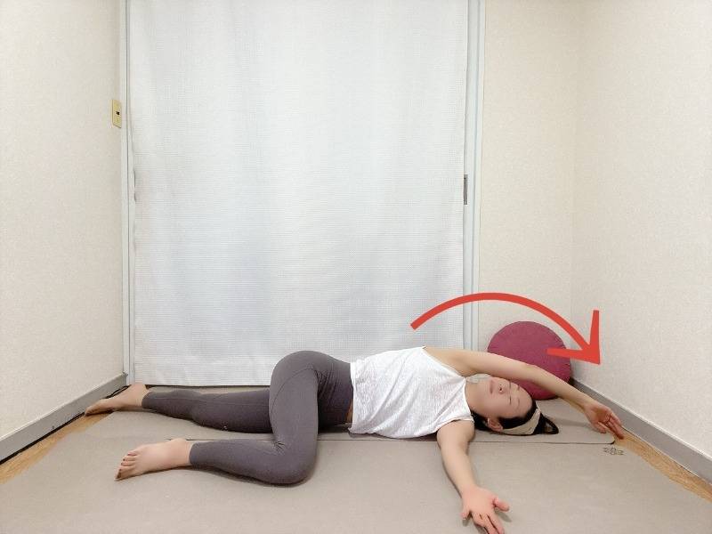 右を下にした横向き寝から左膝を曲げて体の前に置き、左腕を頭上に伸ばした体側のストレッチ