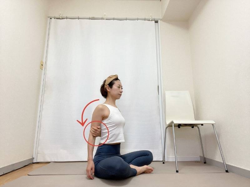 あぐらで座り、右手を背中に回して左肘を掴んだ体勢