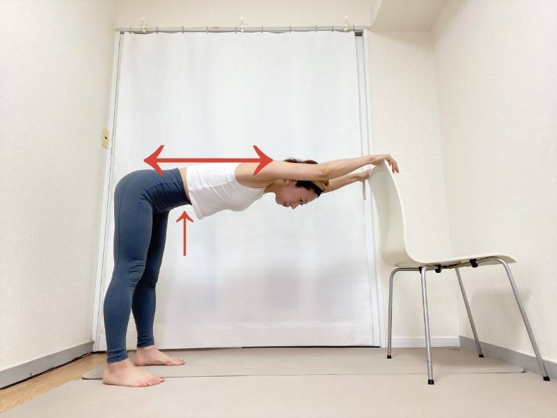 椅子の背もたれに手を置いて後ろに歩いて背中を伸ばすストレッチ