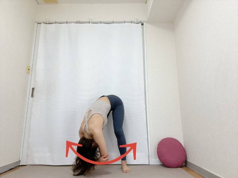 肘を抱え、立って前屈した体勢で上体を左右に揺らすストレッチ