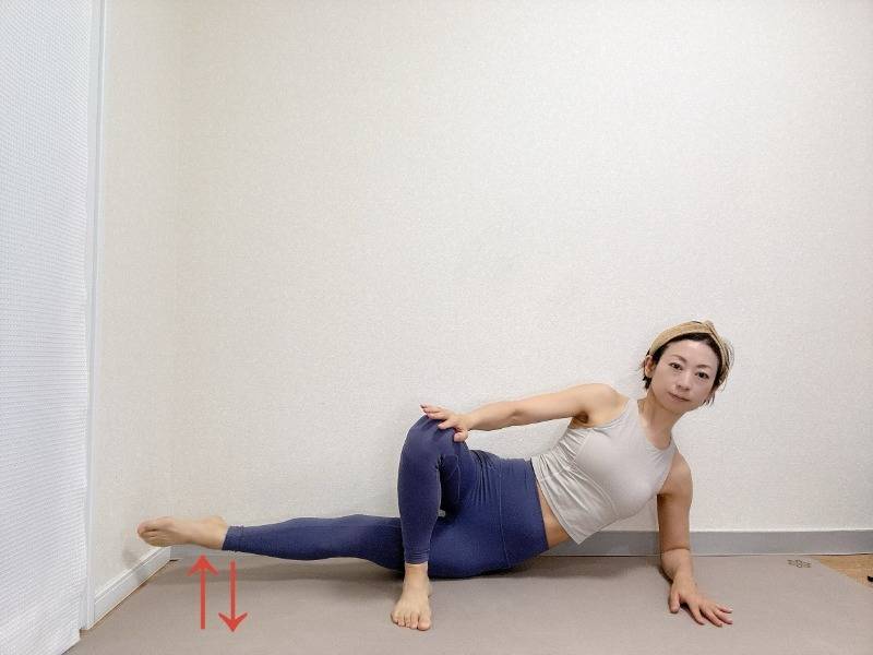 右肘を床に下し、左脚を前に出して右脚を伸ばした横向きの体勢から右脚を床から浮かせる内転筋エクササイズ
