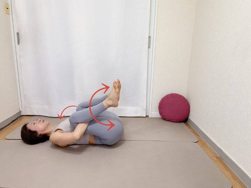 仰向けになり、膝裏を抱えて胸に膝を寄せ、左右に腰を揺らすストレッチ