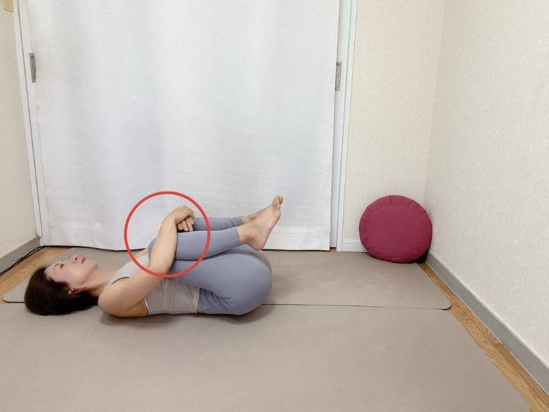 仰向けになり、脛を抱えて膝を胸に寄せるストレッチ