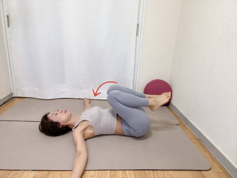 両膝を立て、肩の高さに腕を伸ばした仰向けから胸に膝を引き寄せた体勢