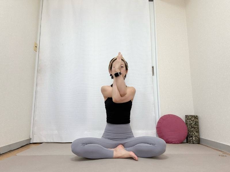 左を上にしたイーグルポーズの腕であぐらで座った体勢