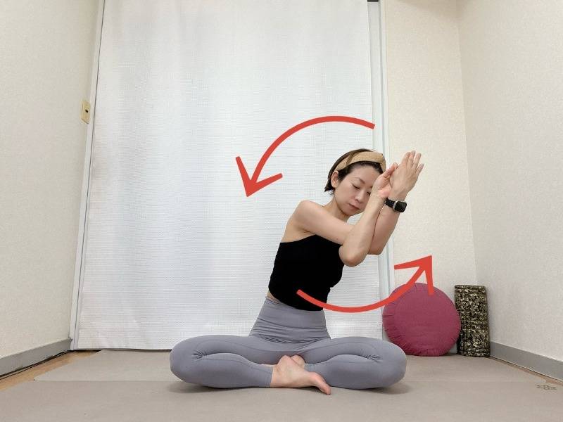 あぐらで座り、左を上にしたイーグルポーズの腕で、左回りに胸の前で円を描くストレッチ