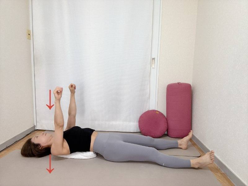 丸めたバスタオルを肩甲骨の下にセットした仰向けから両手を天井に伸ばしたまま肩甲骨をタオルに沈めた体勢