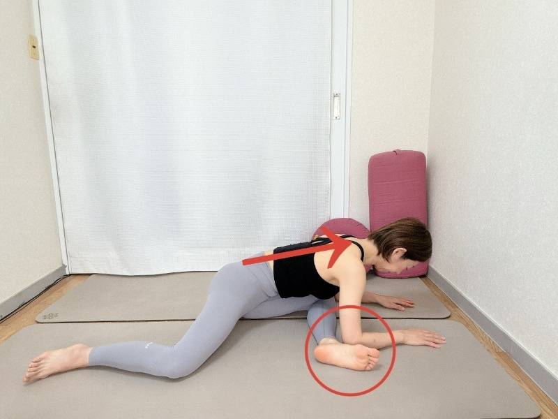 左脚を前、右脚を後ろにして、膝を90度に曲げて座り、背中を伸ばして上体を前に傾け、肘を床について深めるお尻のストレッチ