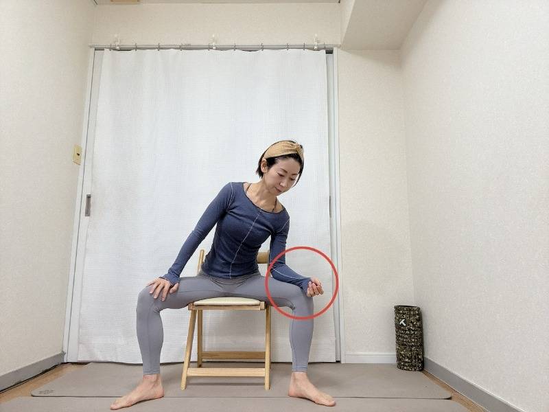 脚を大きく開いて椅子に座り、右腿に肘をついて上体を軽く右に傾けた体勢