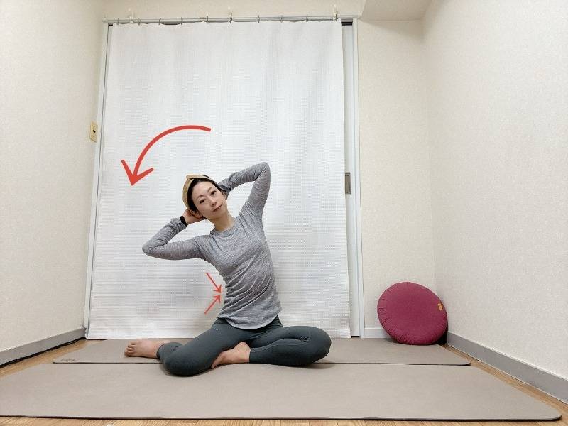 頭の後ろで手を組んで膝下を左に流した横座りから上体を左に傾けて脇腹を縮めるエクササイズ