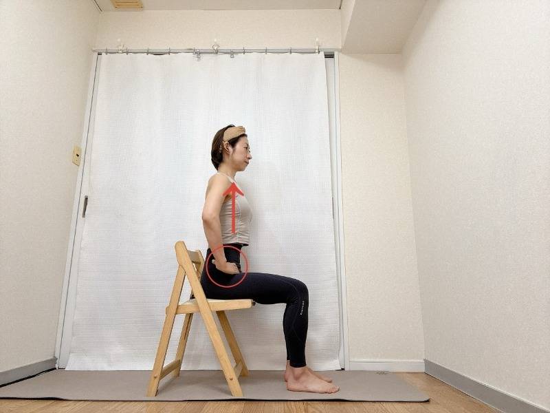 両手を鼠径部に添え、背筋を伸ばして椅子に座った体勢