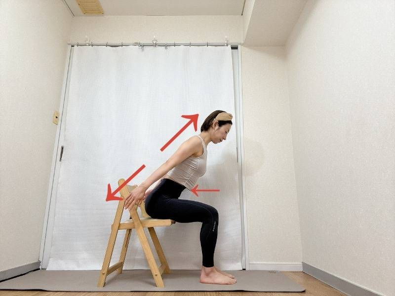 椅子に座り、両手を斜め後ろに下し、上体を前に傾けた体勢