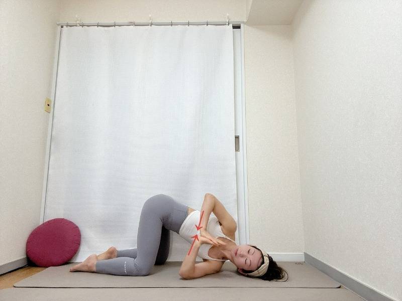 四つ這いで左脇の下から右腕を通したキャットツイストポーズで胸の前で両手を合わせたストレッチエクササイズ