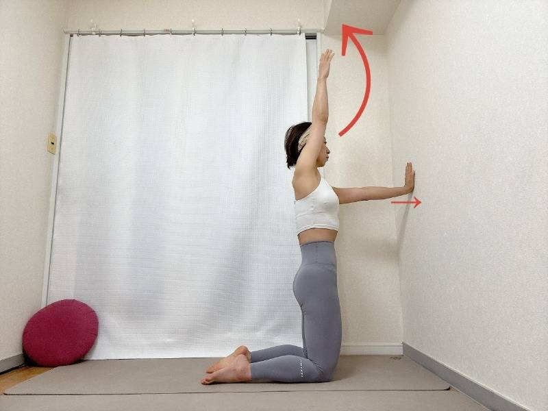 壁に向かって膝立ちになり、片手を天井方向に上げた体勢