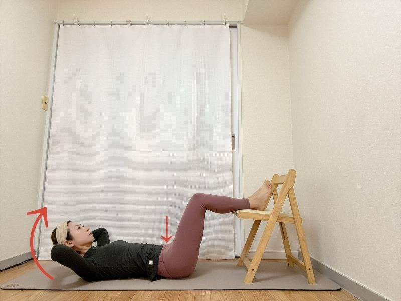 ふくらはぎから下を椅子に乗せ、頭の後ろ手に手を添えた仰向けから、上や胃を軽く浮かせる腹筋エクササイズ