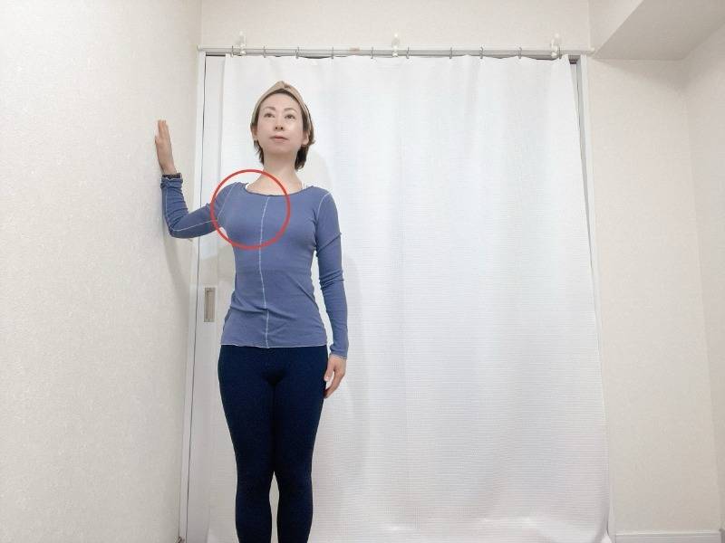 左肘を９０度に曲げて壁に腕をつけ、一歩前に進んで肩や胸を開くストレッチ