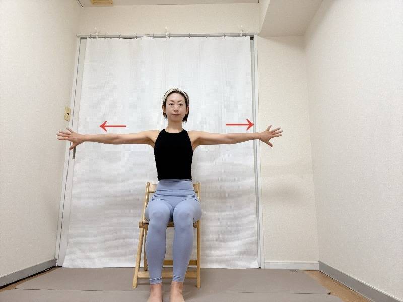 椅子に座り、手の甲を前に向けて両手を肩の高さで開いた体勢