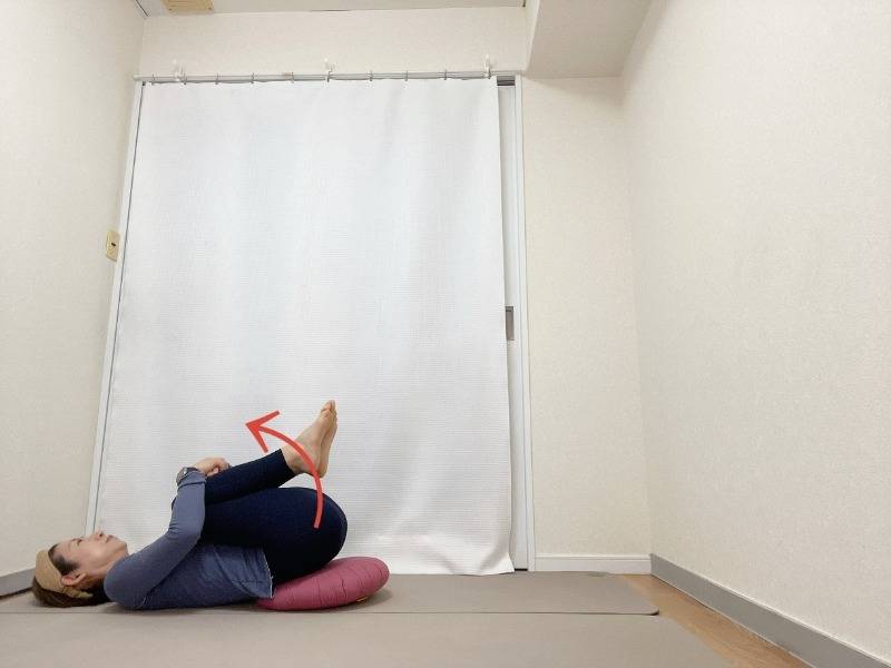 お尻の下にクッションを敷いて両膝を胸に抱えた仰向けの体勢