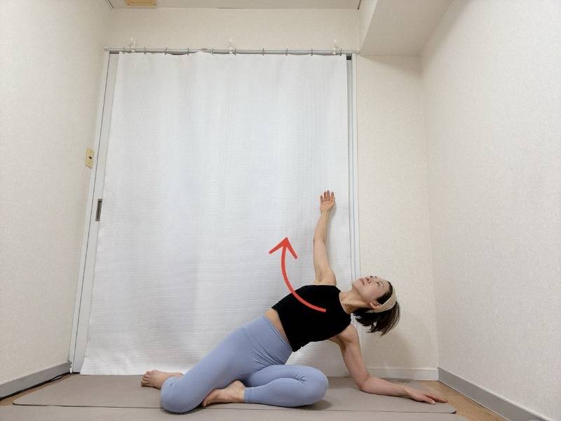 膝下を左に流した横座りから、右肘を床に下し、左手を斜め上に引き上げて体側を伸ばした体勢