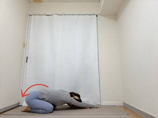 左手を右手の前に着いた四つ這いからお尻をかかとに下した背骨のストレッチ