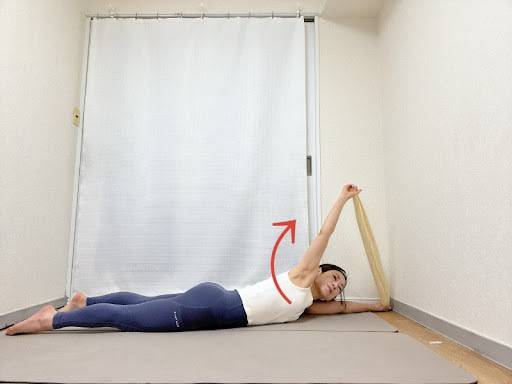 たおるの両端を持ったうつ伏せから、左手を引き上げて胸を開くストレッチ