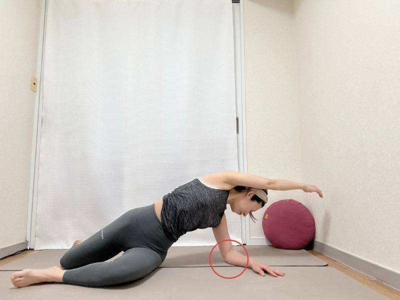 膝を立てて座っり、右肘を後ろの床に下して左手を引き上げ、両膝を右に倒して後ろを振り返って左腰から体側を伸ばすストレッチ