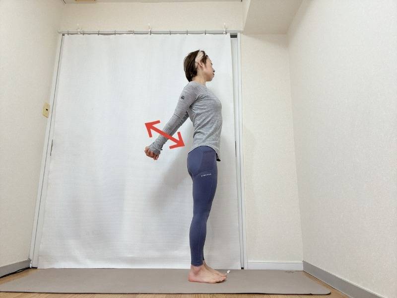 両手を背中の後ろで組み、肩や肩甲骨を下して握った手を上下に動かすストレッチ。