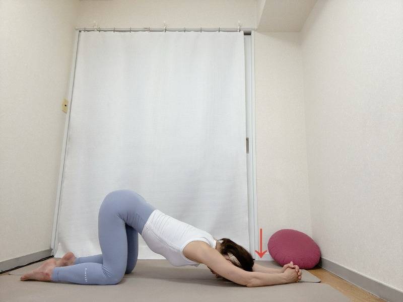 両手を組んで肘をついた四つ這いからおでこを床に下し、背骨を伸ばすストレッチ