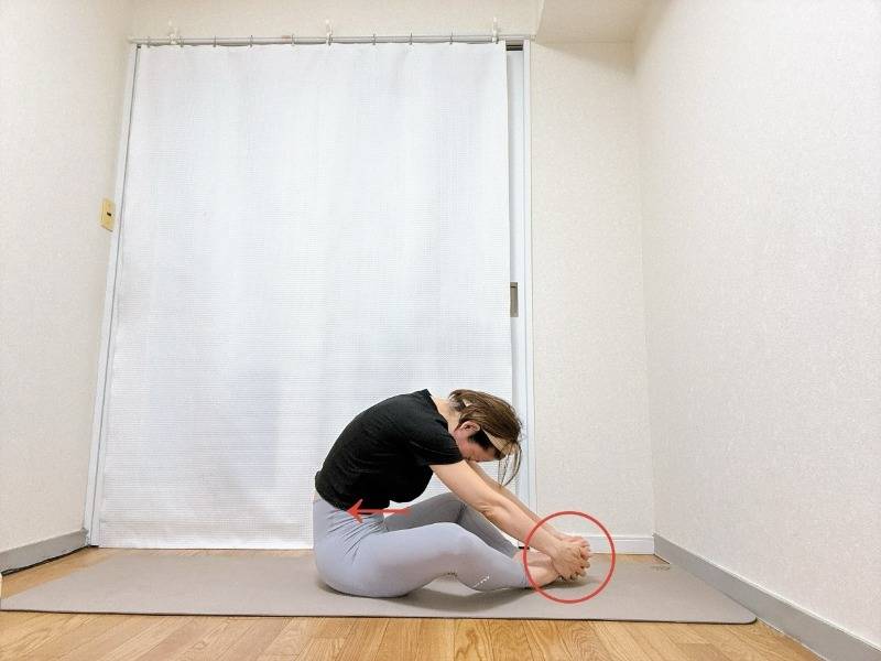 両手でつま先を掴んだがっせきからお腹を引き込んで骨盤を後ろに倒して背中を丸めて座った体勢