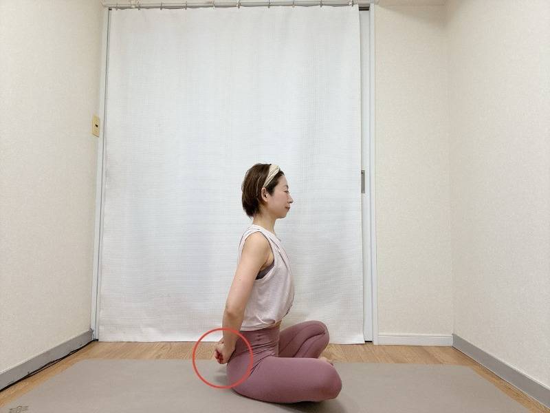肘を曲げ、軽く手を握って腰に添え、あぐらで座った体勢